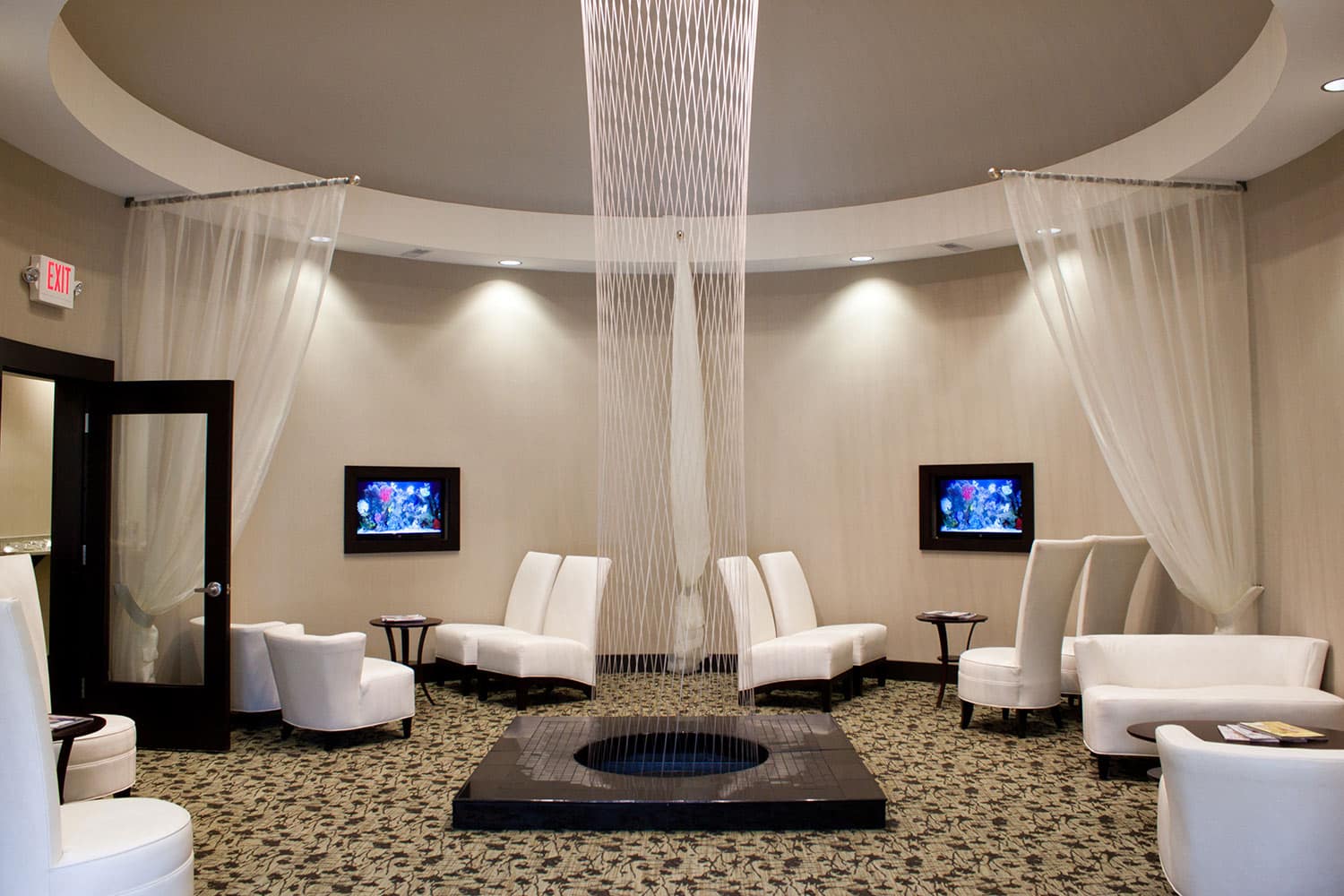 Cozy room with white chairs and a TV on the wall.